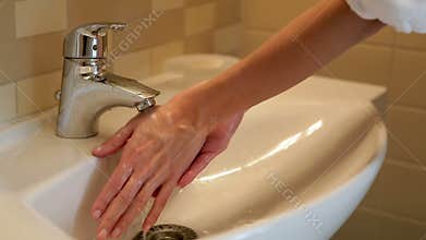 Girl washes her hands under the tap