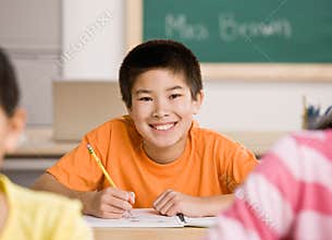 Student writing in notebook in school classroom