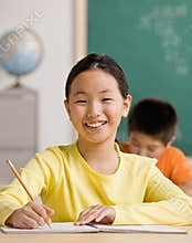 Student writing in notebook in school classroom