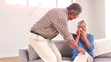 Mature man comforting his wife crying on the couch