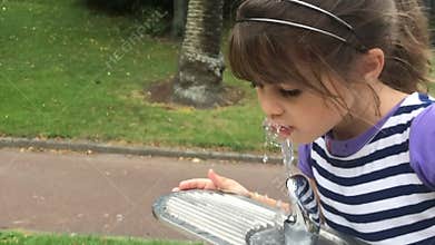 Girl drink water from drinking fountain.