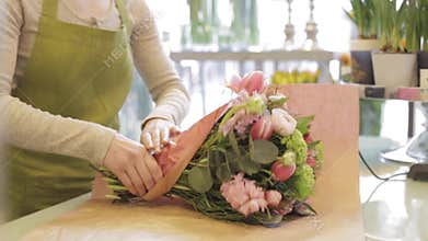 Florist wrapping flowers in paper at flower shop