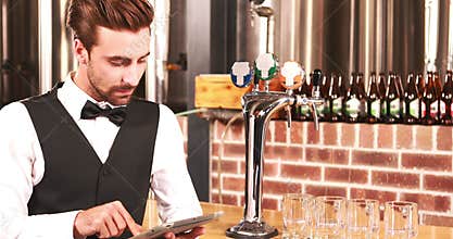 Smiling barkeeper using tablet well dressed