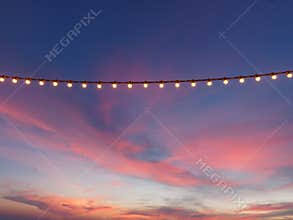 Light bulbs on string wire against sunset sky