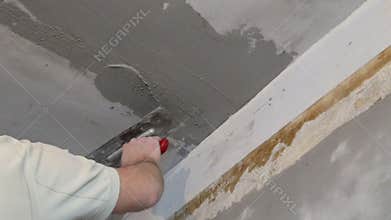Builders float in hand applying plaster on the ceiling