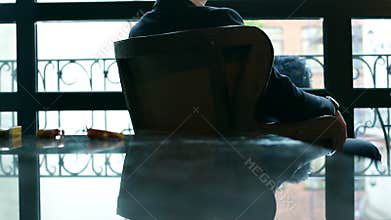 Thoughtful businessman sitting on a chair by the window.
