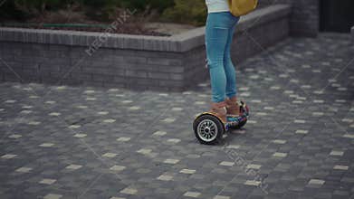 Modern young girl with a bright yellow backpack rides on hoverboard
