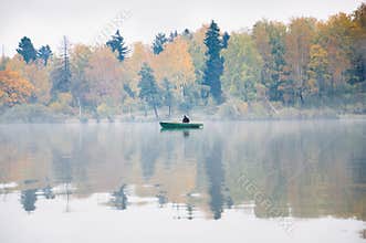 Fishing on the lake Senezh in Solnechnogorsk in the fall. The fog, the wind, the silhouette of a fisherman in a boat