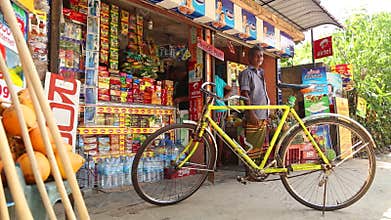MIRISSA, SRI LANKA - MARCH 2014: Bike parked outside a local shop with man standing in background on the street in Mirissa.
