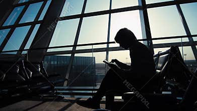 Businessman using tablet computer at the airport. silhouette of a man traveler with backpack. business and travel