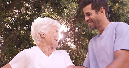 Male nurse assisting a senior woman to walk in the backyard