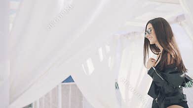 girl in black and sunglasses posing near the sea in white gazebo. 4K