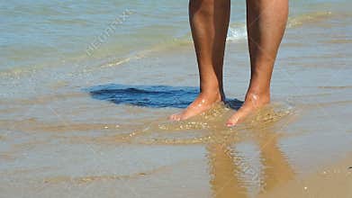 Woman legs standing on waterline