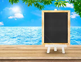 Blackboard menu with easel on wood table at sea with tree and sun burst, Copy space for adding your content
