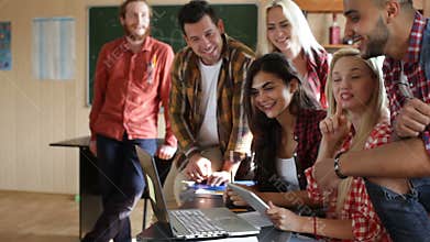 Students excited watching video using tablet computer and laptop university