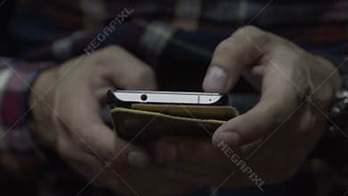 The man in the hands of the phone. The guy sitting on a chair holding a smartphone
