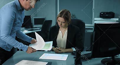 4K: An older colleague explains a new employee how to analyze the financial reports