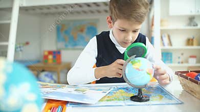 Schoolboy and geographical atlas. The boy student studying geography.