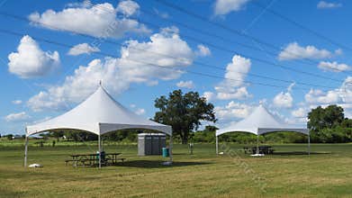 Two canopies three porta pottys and power lines