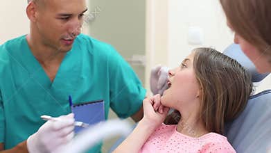 Close up of cute girl at dentist shows with finger aching tooth