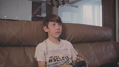 Boy playing video games on the console the on the sofa at home