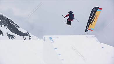 Skier in uniform jump from springboard. Extreme stunt. Snowy mountains. Challenge. Landscape