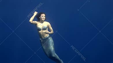 Young girl model underwater seamaiden costume on blue background in Red Sea.