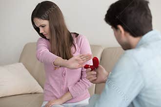 Young man making marriage proposal, engagement ring, lady reject