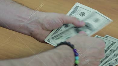 Men`s hands with a bracelet count the bills