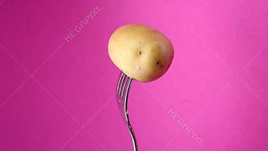 Rotating fork with potatoes on purple background
