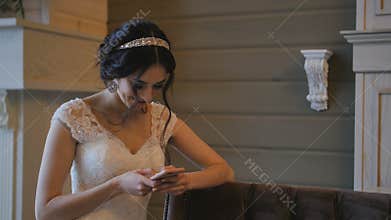 Young bride on wedding day using mobile phone
