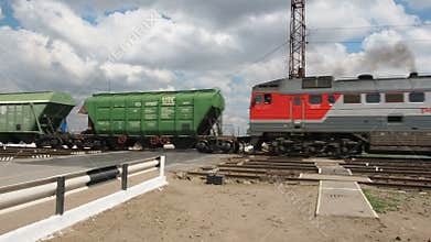 Diesel railcars travelling through moving. The locomotive travels through the crossing.