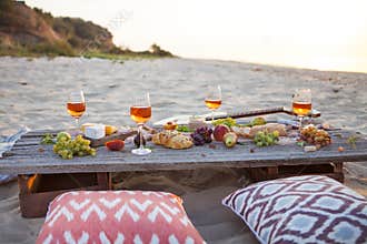 Picnic on the beach at sunset in boho style, food and drink conc