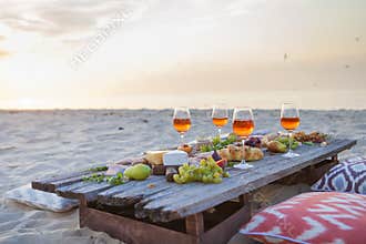 Picnic on the beach at sunset in boho style, food and drink conc