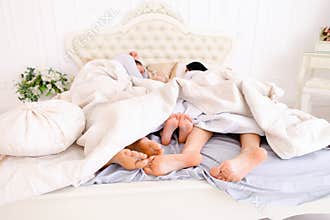 Close-up family feet that lie and sleep on bed