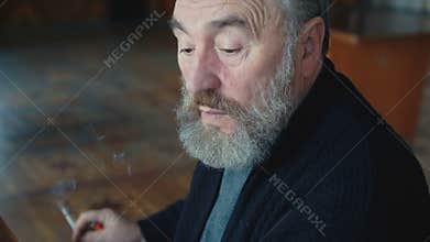 Emotional tired old man sitting, smoking cigarette thinking, scratching ear 4K