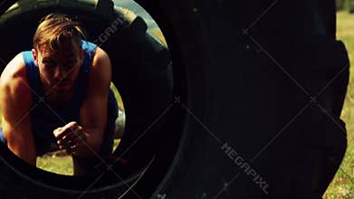 Man crawling through the tires during obstacle course