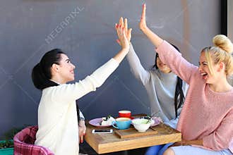 Three young lovely girls girlfriends chatter, rejoice, high five