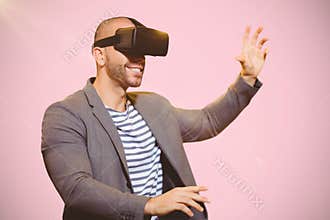 Composite image of businessman holding virtual glasses on a pink background