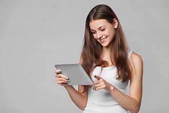 Happy girl in white shirt using tablet. Smiling woman with tablet pc, isolated on grey background