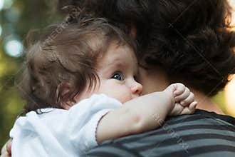 Little Girl resting on her father`s shoulder. Happy sweet girl hugging her father on the forest background