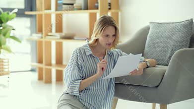 Beautiful young lady checking business documents at home