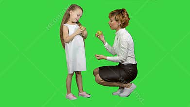 Happy mother with daughter eating healthy food on a green screen, chroma key