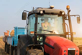 Beautiful, young farmer girl is driving tractor