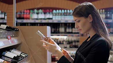 Young Beautiful Woman Chooses Wine In The Supermarket. Businesswoman in wine shop.
