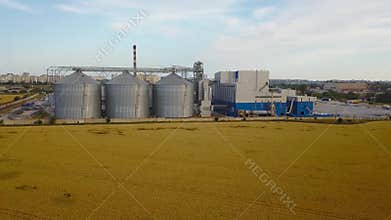 Aerial of big steel grain silos elevators storage at the yellow wheat field. Agriculture industry 4k aerial video of