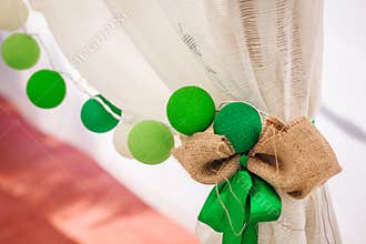 Cotton balls garland hangs on a white curtain. Bright colored decoration. Wedding