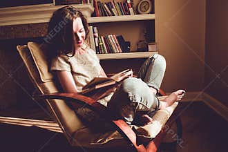 Spending free time by reading books. Home and comfort concept. Woman smiling reads interesting book in comfortable modern chair. N