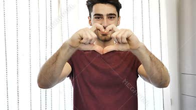 Handsome young man making heart sign with hands