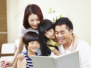 Happy asian family reading a book at home